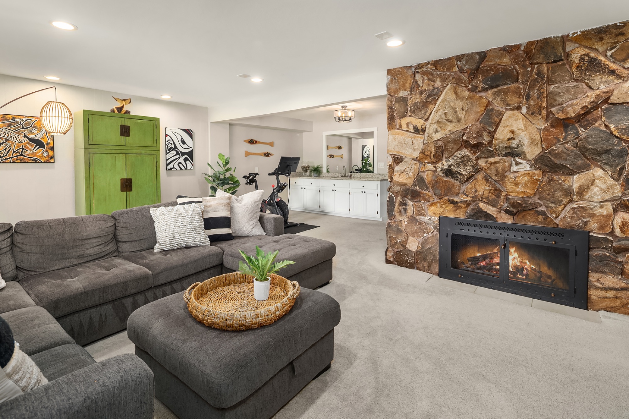 Lower level rec room with sectional and stone fireplace