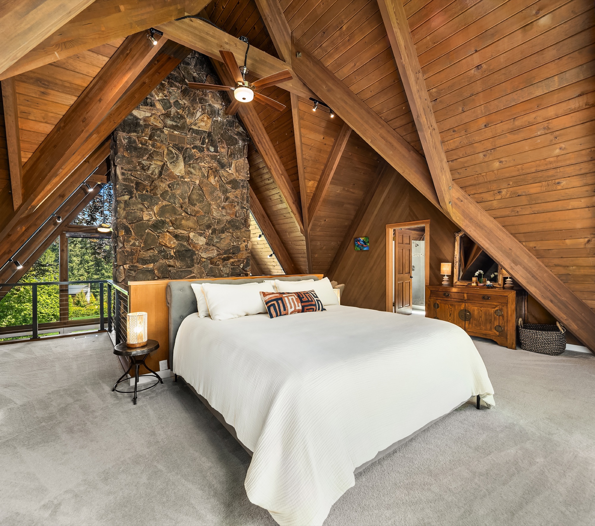 Primary bedroom beneath the A-frame peak with stone wall